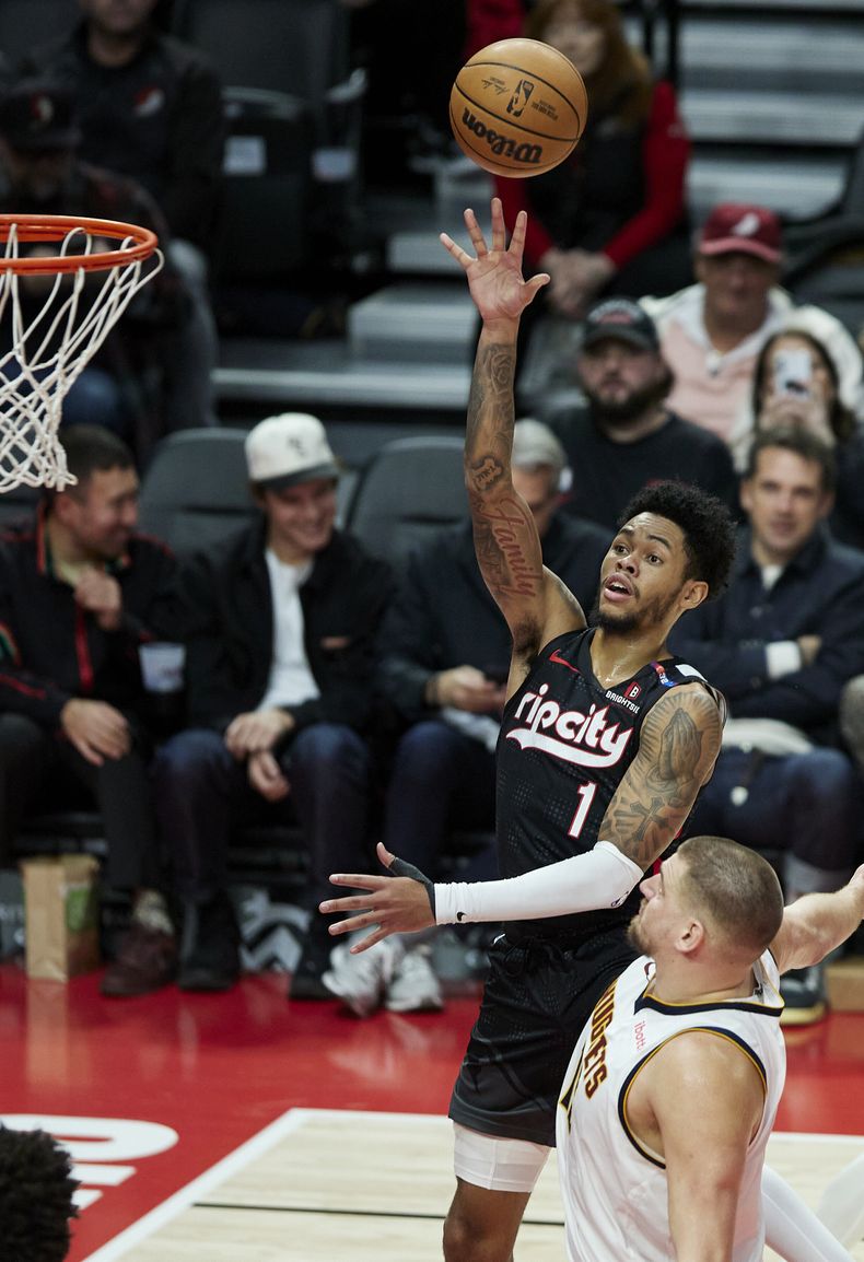 El base de los Trail Blazers de Portland Anfernee Simons lanza el balón sobre el píbot de los Nuggets de Denver Nikola Jokic en el encuentro del jueves 19 de diciembre del 2024. (AP Foto/Craig Mitchelldyer)