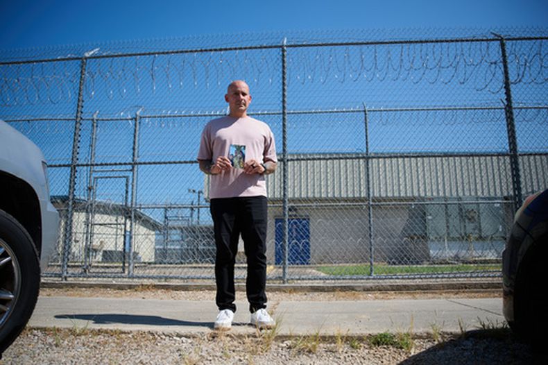 El sargento del Ejército Alexis Jaramillo posa con una foto de su esposa, Maisa Lopes Eliaser, una ciudadana brasileña que está detenida por ICE, antes de visitarla en el centro de procesamiento de ICE de South Louisiana, en Basile, Luisiana, el 2 de agosto de 2026. (AP Foto/Joseph Vidrine)