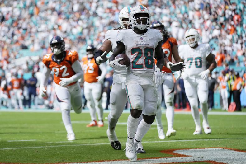 El running back DeVon Achane (28) de los Dolphins de Miami celebra tras anotar un touchdown ante los Broncos de Denver, el domingo 24 de septiembre de 2023, en Miami Gardens. (AP Foto/Rebecca Blackwell)