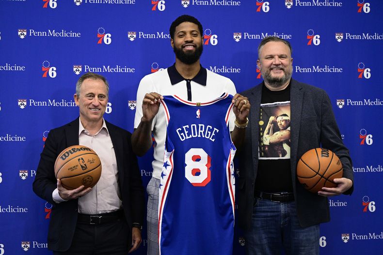 Paul George, pívot de los 76ers de Filadelfia, el propietario Josh Harris, a la izquierda, y el presidente Daryl Morey posan para una foto en las instalaciones de práctica del equipo de baloncesto de la NBA, el martes 23 de julio de 2024, en Camden, Nueva Jersey (AP Foto/Derik Hamilton)