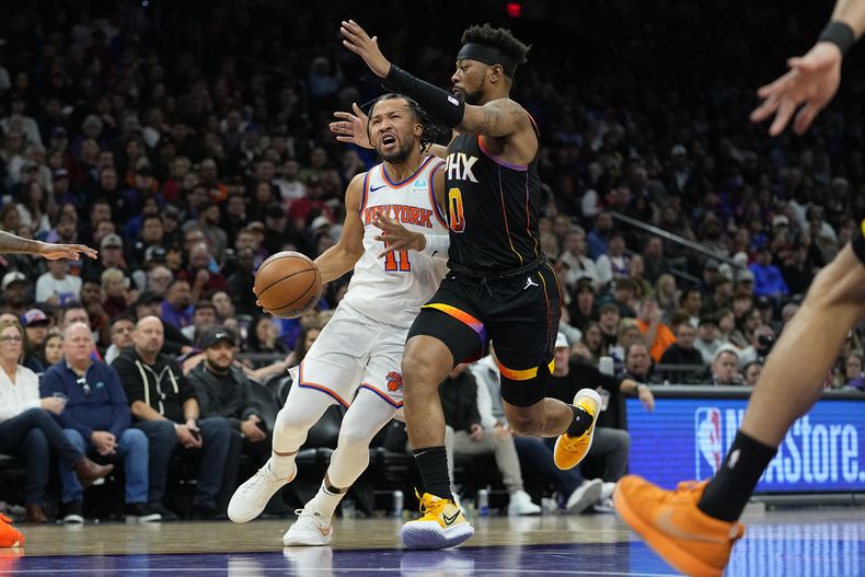 Jalen Brunson, base de los Knicks de Nueva York, conduce el balón frente a Jordan Goodwin, de los Suns de Phoenix, en el partido del viernes 15 de diciembre de 2023 (AP Foto/Matt York)