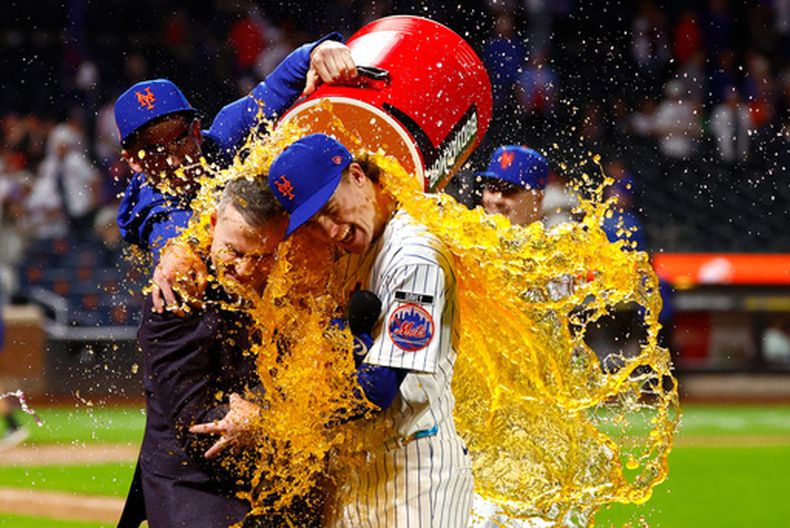 El pelotero de los Mets de Nueva York Carson Benge (derecha) abraza al narrador Steve Gelbs (izquierda) mientras es bañado con Gatorade tras romper el récord de la franquicia de los Mets de más hits en una temporada para un novato, el sábado 19 de septiembre de 2026, en Nueva York. (Foto AP/Noah K. Murray)
