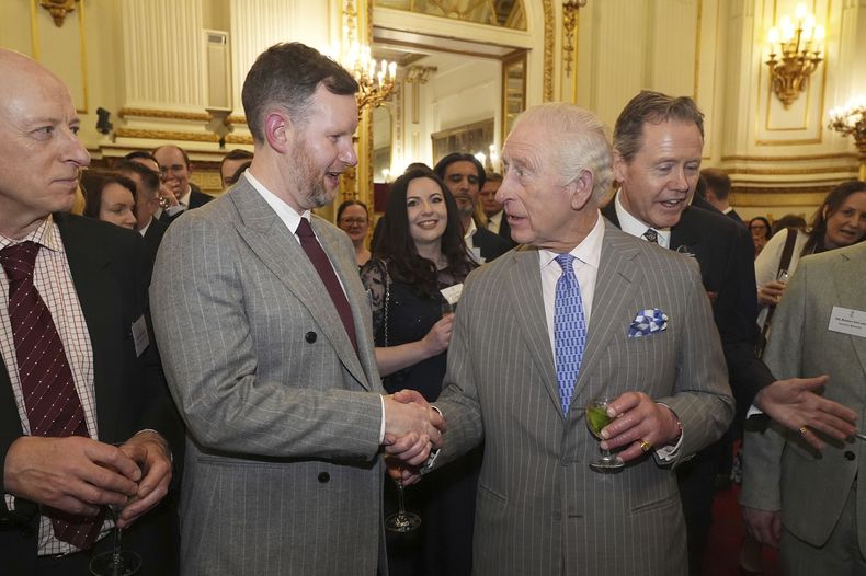 El rey Carlos III de Gran Bretaña saluda a un invitado durante una recepción en el Palacio de Buckingham, Londres, para invitados de una amplia gama de organizaciones de medios de todo el país, el miércoles 26 de marzo de 2025. (Aaron Chown, Pool via AP)