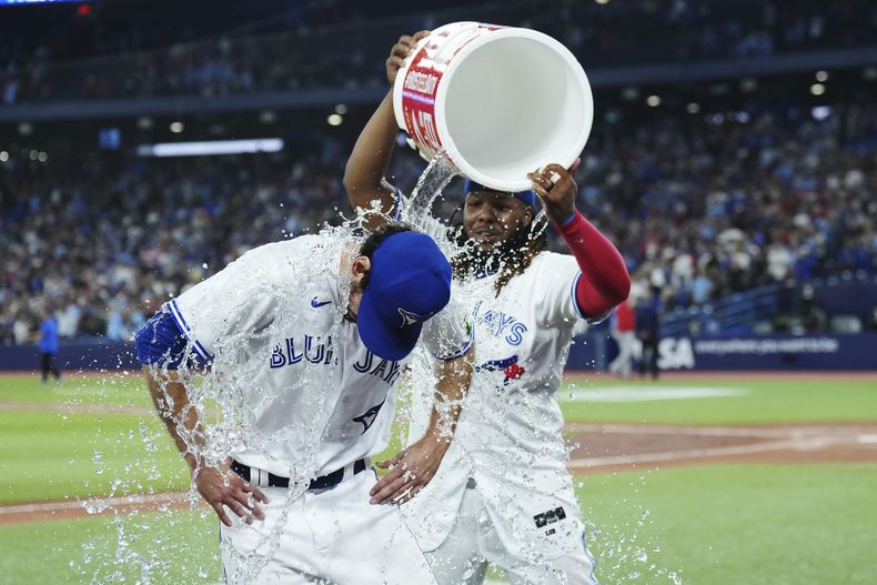 El relevista de los Azulejos de Toronto Jordan Romano es bañado por un cubetazo con agua por suu compañero Vladimir Guerrero Jr. luego de vencer a los Filis de Filadelfia, en Toronto. Martes 15 de agosto de 2023. (Nathan Denette/The Canadian Press via AP)