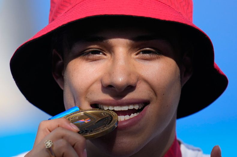 El mexicano Osmar Olvera muerde su medalla de oro durante la premiación del trampolín de 3 metros de los Juegos Centroamericanos y del Caribe, el sábado 1 de agosto de 2026, en Santo Domingo. (AP Foto/Fernando Vergara)