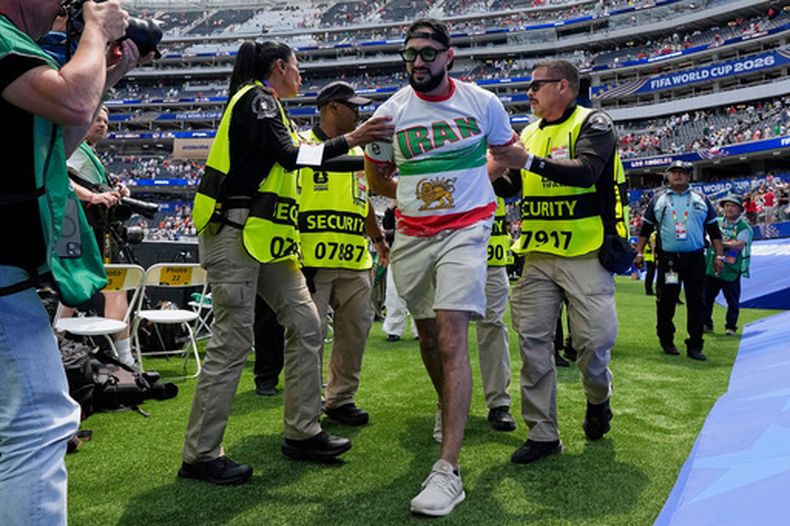 Un aficionado iraní es retirado de la cancha por empleados de seguridad al final del partido entre la selección de su país y Bélgica en Inglewood, California, el domingo 21 de junio de 2026 (AP Foto/Gregory Bull)