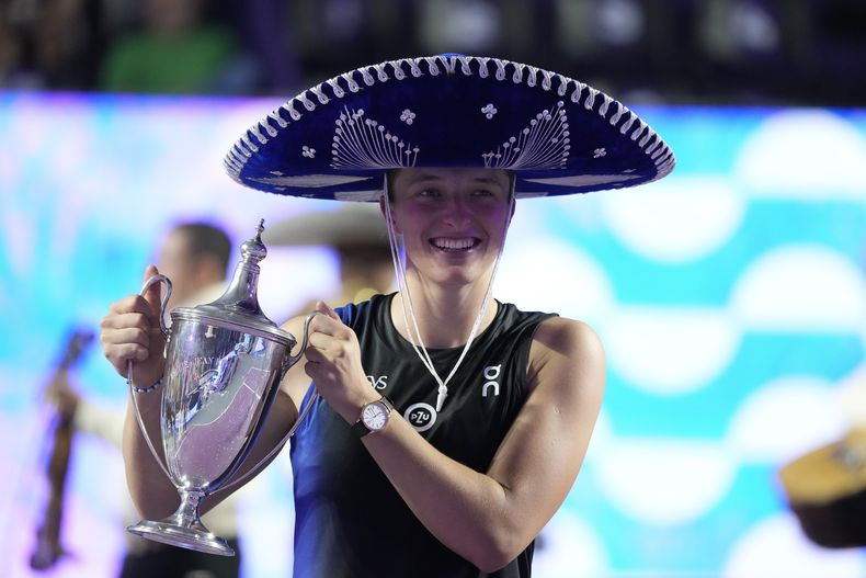 Iga Swiatek, de Polonia, sostiene el trofeo que la acredita como campeona del torneo que cierra la temporada, las Finales de la WTA, después de derrotar a Jessica Pegula, de Estados Unidos, en Cancún, México, el lunes 6 de noviembre de 2023. (AP Foto/Fernando Llano)