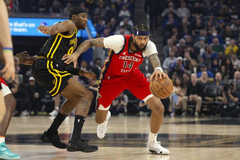 Brandon Ingram (14), alero de los Pelicans de Nueva Orleans, conduce el balón con la presión de Jonathan Kuminga (00), de los Warriors de Golden State, durante el primer cuarto del juego de baloncesto de la NBA, el miércoles 10 de enero de 2024, en San Francisco. (AP Foto/D. Ross Cameron)