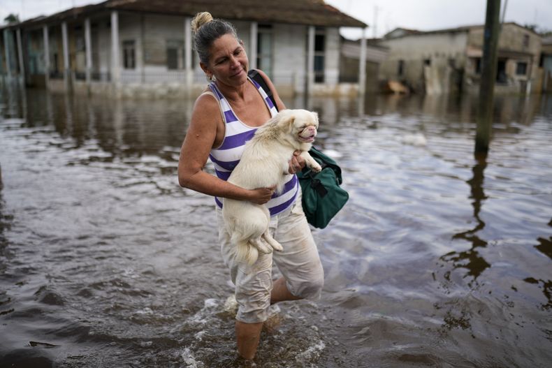 Madeleine Mur lleva a su perro por una calle inundada tras el paso del huracán Rafael por Batabanó, Cuba, el jueves 7 de noviembre de 2024. (Foto AP/Ramón Espinosa)