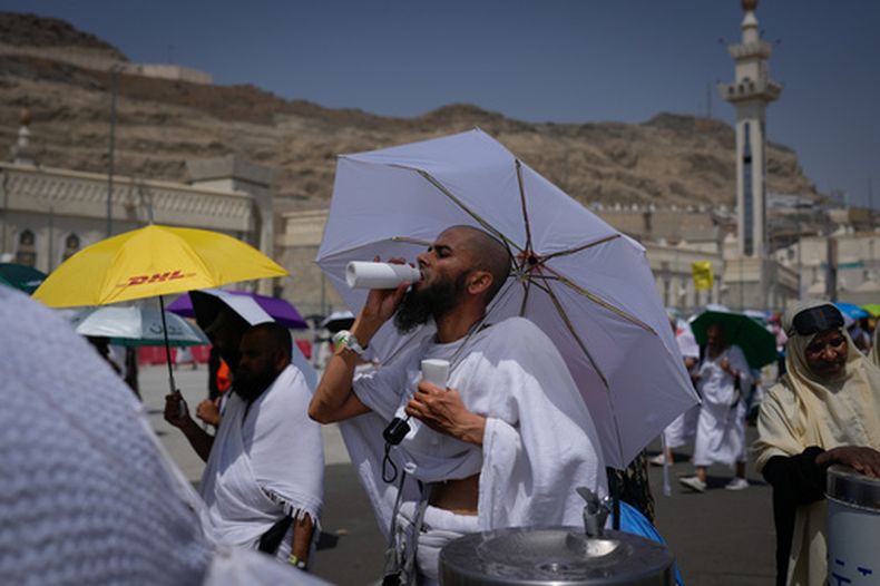 Un peregrino musulmán bebe agua mientras camina junto con otros fieles al lugar donde arrojarán piedras a columnas para simbolizar la lapidación del diablo, el último rito de la peregrinación anual del haj, en Mina, cerca de la ciudad santa de La Meca, Arabia Saudí, el 27 de mayo de 2026. (AP Foto/Altaf Qadri)