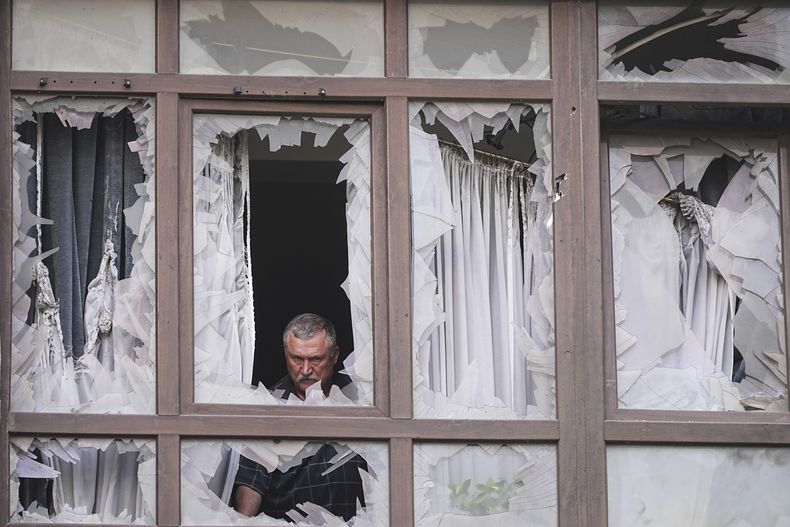 Un hombre, detrás de las ventanas rotas de su casa tras un ataque ruso en Kiev, Ucrania, el 21 de julio de 2025. (AP Foto/Efrem Lukatsky)