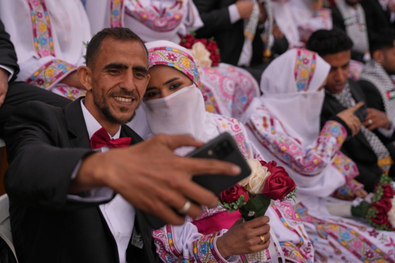 Una pareja palestina posa para una selfi mientras se casan en una ceremonia masiva en Deir al-Balah, en el centro de la Franja de Gaza, el viernes 24 de abril de 2026. (AP Foto/Abdel Kareem Hana)