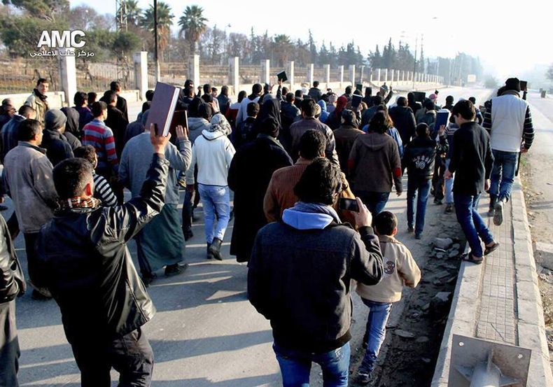 Una imagen de periodistas ciudadanos cedida por el Centro de Medios de Alepo, que ha sido autentificada por su contenido y reportajes de la AP, muestra a sirios con el Cor&aacute;n durante una manifestaci&oacute;n para detener los combates entre el EIIL y