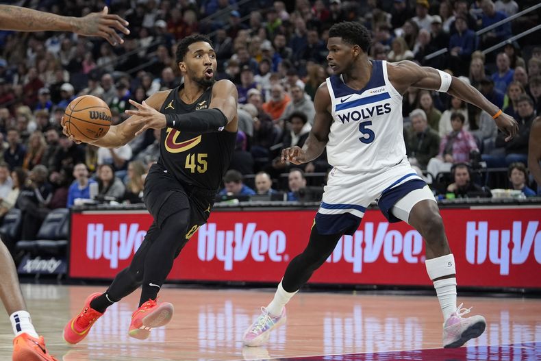 El escolta de los Cavaliers de Cleveland, Donovan Mitchell (45), avanza hacia la canasta mientras el escolta de los Timberwolves de Minnesota, Anthony Edwards (5), defiende durante la primera mitad de un partido de baloncesto de la NBA, el sábado 18 de enero de 2025, en Minneapolis. (AP Foto/Abbie Parr)
