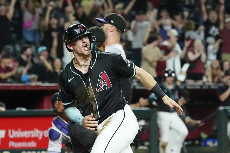 Kevin Newman, de los Diamondbacks de Arizona, celebra después de anotar carrera con un lanzamiento descontrolado de los Rockies de Colorado durante la séptima entrada del juego de béisbol del lunes 12 de agosto de 2024, en Phoenix. (AP Foto/Ross D. Franklin)