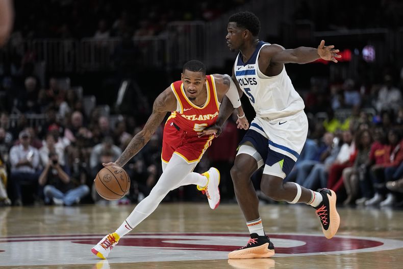 Dejounte Murray (5), de los Hawks de Atlanta, conduce el balón ante la marca de Anthony Edwards (5), de los Timberwolves de Minnesota, durante la primera mitad del juego de baloncesto de la NBA, el lunes 30 de octubre de 2023, en Atlanta. (AP Foto/John Bazemore)