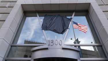 La bandera estadounidense junto a una asta vacía que sostenía la bandera de la Agencia de los Estados Unidos para el Desarrollo Internacional (USAID, por sus siglas en inglés), se refleja en una ventana que mostraba el nombre y el sello de la USAID, fuera de las oficinas de la agencia en Washington, el viernes 7 de febrero de 2025. (AP Foto/Jose Luis Magana)