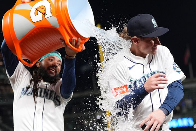 Colt Emerson, derecha, de los Marineros de Seattle, recibe un baño por parte de su compañero de equipo J.P. Crawford, para celebrar la victoria sobre los Medias Blancas de Chicago, el lunes 18 de mayo de 2026, en Seattle. (AP Foto/Lindsey Wasson)