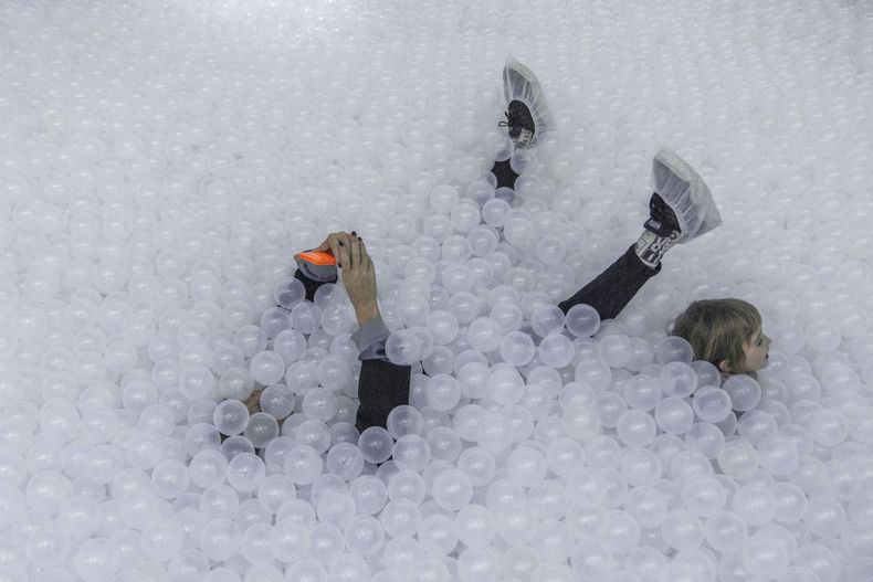 Una mujer se toma una selfie tumbada dentro en una piscina de bolas de plástico que forma parte de la Blow Up Experience, una muestra de arte y tecnología inflable, en Montevideo, Uruguay, el 30 de agosto de 2024. (AP Foto/Matilde Campodonico)