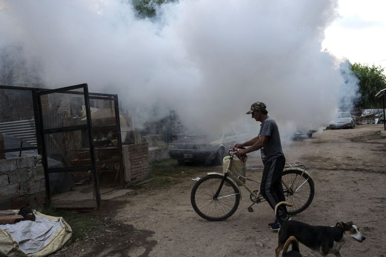 Un hombre camina con su bicicleta entre nubes de insecticida durante una campaña de fumigación para contener el dengue, en Rosario, Argentina, el martes 4 de abril de 2023. (Foto AP/Rodrigo Abd)