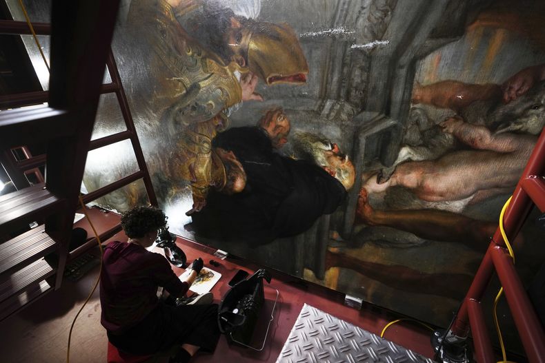 La restauradora de arte Jill Keppens trabaja en una sección de Madona entronizada con niño, rodeada de santos, pintada por el artista flamenco Peter Paul Rubens, en el Museo Real de Bellas Artes de Amberes, Bélgica, el martes 28 de enero de 2025. (Foto AP/Virginia Mayo)