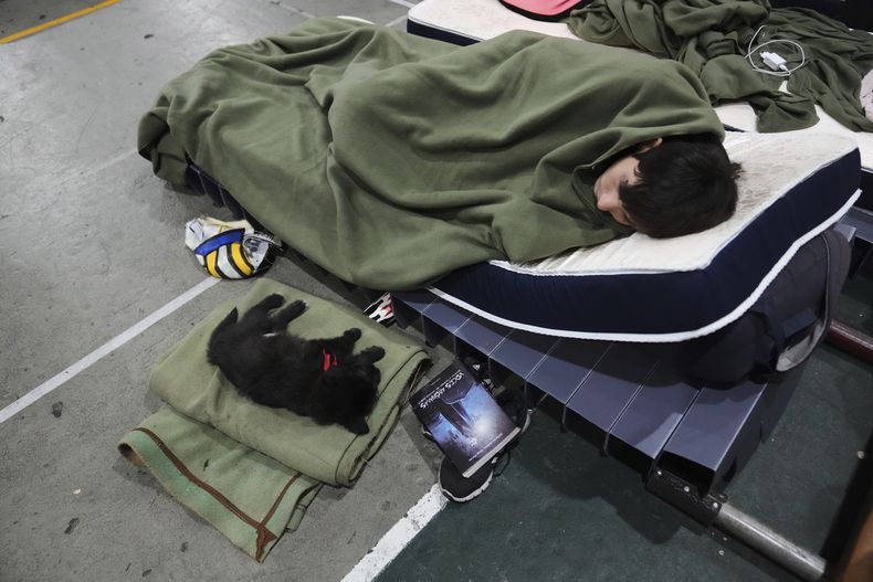 Lucas Bilhere y su perro Alaska descansan en un gimnasio que el gobierno está utilizando como refugio improvisado en un esfuerzo por proteger a las personas sin hogar del frío en Montevideo, Uruguay, el miércoles 25 de junio de 2025. (AP Foto/Matilde Campodonico)