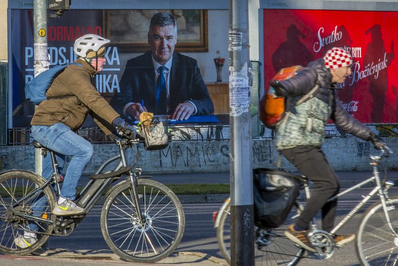 Ciclistas pasan junto a un cartel del actual presidente Zoran Milanovic antes de las elecciones presidenciales en Zagreb, Croacia, el jueves 26 de diciembre de 2024. (AP foto)