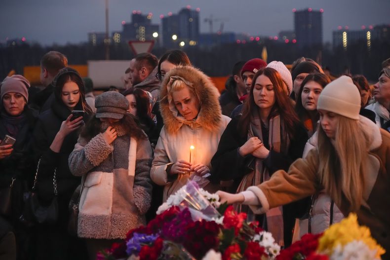 Varias personas depositan flores y encienden velas el 23 de marzo de 2024 en las inmediaciones del Crocus City Hall, donde se registró un ataque que dejó más de 100 fallecidos, a las afueras de Moscú, Rusia. (AP Foto/Alexander Zemlianichenko)