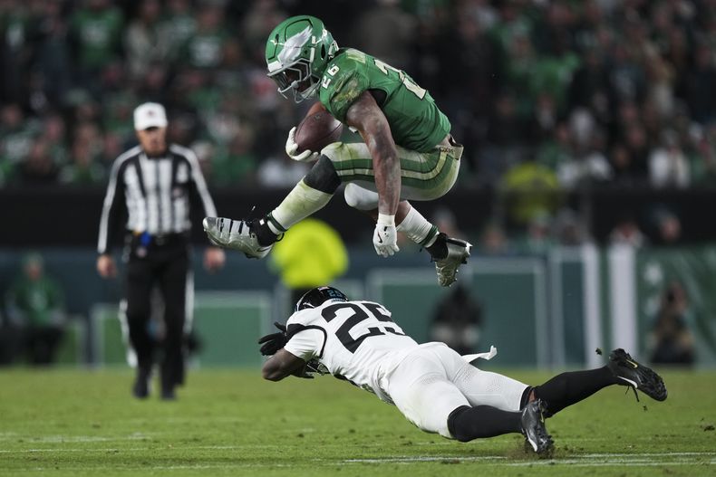 Saquon Barkley (26), running back de los Eagles de Filadelfia, brinca sobre el cornerback Ronald Darby (25), de los Jaguars de Jacksonville, durante la segunda mitad del juego de la NFL, el domingo 3 de noviembre de 2024, en Filadelfia. (AP Foto/Matt Slocum)