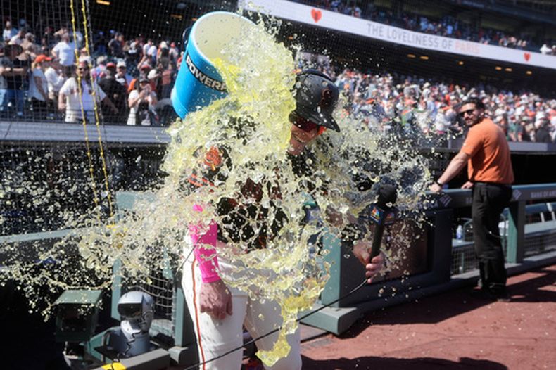 Harrison Bader, de los Gigantes de San Francisco, es empapado con la hielera por el dominicano Willy Adames, tras el duelo del sábado 23 de mayo de 2026 ante los Medias Blancas de Chicago (AP Foto/Jeff Chiu)