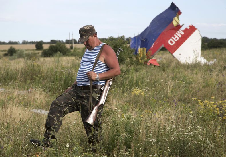 Un combatiente pro ruso camina frente a uno de los restos del derribado avi&oacute;n de Malaysia Airlines cerca del poblado de Hrabove, UCrania, el lunes 21 de julio de 2014. (Foto AP/Dmitry Lovetsky)