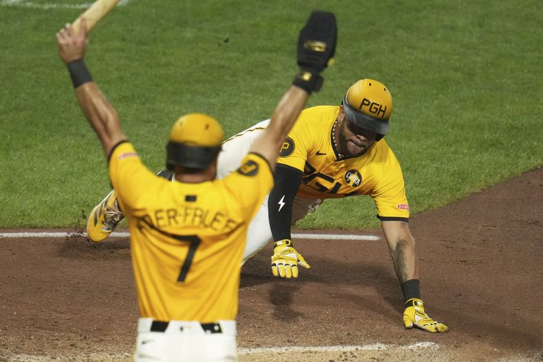 Tommy Pham, derecha, llega barrido a salvo al plato con la segunda carrera impulsada por un triple de Bryan Reynolds frente al lanzador de los Rojos de Cincinnati Tony Santillan durante la octava entrada del juego de béisbol de Grandes Ligas el viernes 8 de agosto de 2025, en Pittsburgh. (AP Foto/Gene J. Puskar)