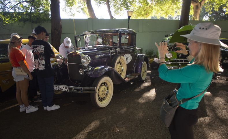 Una turista toma una fotografía de un Ford de los años de 1930, antes del inicio del Rally de Autos Antiguos de La Habana, en La Habana, Cuba, el domingo 3 de diciembre de 2023. (Foto AP/Ismael Francisco)