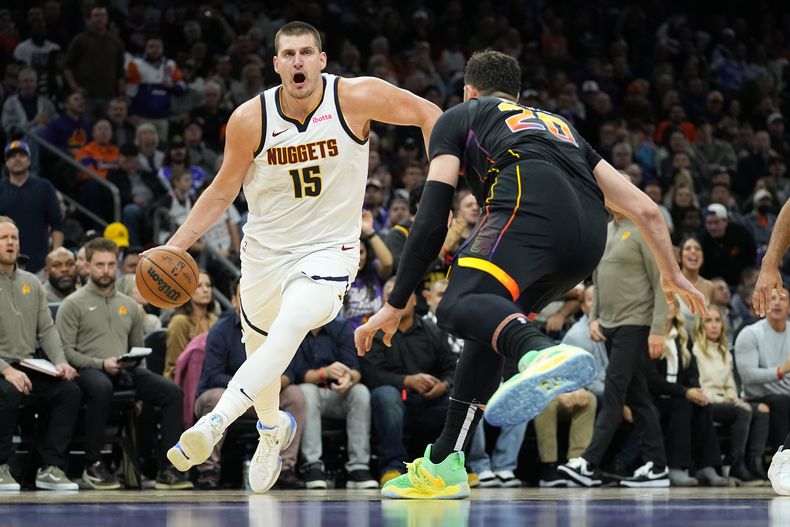 El pívot de los Nuggets de Denver Nikola Jokic avanza hacia la canasta superando al pívot de los Suns de Phoenix Jusuf Nurkic en el encuentro del viernes 1 de diciembre del 2023. (AP Foto/Matt York)