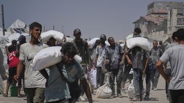 Palestinos cargan sacos de harina descargados por un convoy de ayuda humanitaria que llegó a Ciudad de Gaza desde el norte de la Franja de Gaza, el domingo 27 de julio de 2025. (AP Foto/Abdel Kareem Hana)