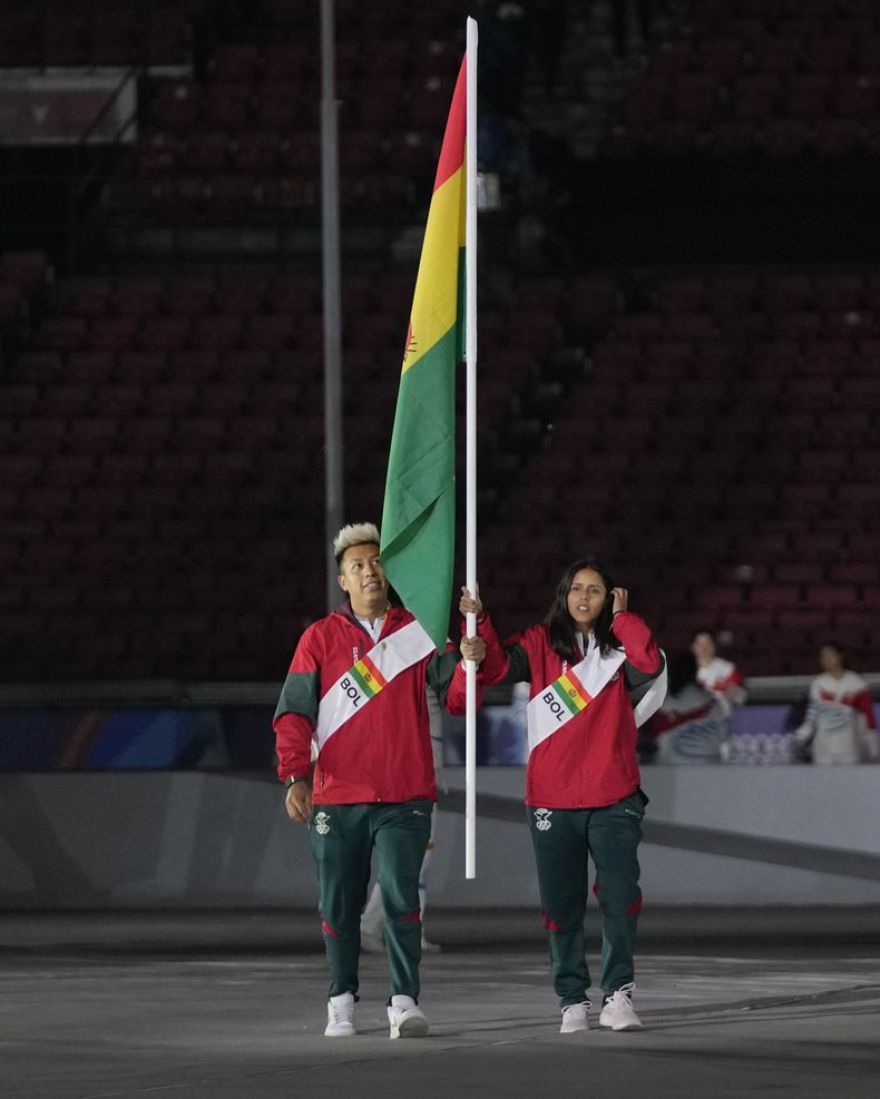 Conrrado Moscoso (izquierda) y Noelia Zeballos portan la bandera de Bolivia durante la ceremonia de apertura de los Juegos Panamericanos en Santiago, Chile, el viernes 20 de octubre de 2023. (AP Foto/Fernando Vergara)