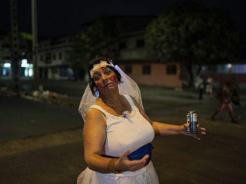 Elisheva Rose, que se viste de novia para ayudar a llevar clientes al puesto de tamales de su esposo, es sorprendida por la cámara con una bebida energética en la mano, en Durán, una ciudad ubicada frente a Guayaquil, Ecuador, el 2y de septiembre de 2023. Esta maestra de Inglés y Arte natural de Sudáfrica contó que se mudó a Ecuador porque su esposo es ecuatoriano-israelí, pero ahora quieren mudarse de país por el aumento de la delincuencia. (AP Foto/Rodrigo Abd)