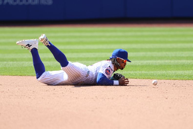Francisco Lindor, campocorte de los Mets de Nueva York, se lanza para tratar de tomar una pelota bateada por Romy Gonzalez, de los Medias Rojas de Boston, lo que permitió que Ceddanne Rafaela llegara a segunda base durante la novena entrada del juego de béisbol de Grandes Ligas, el domingo 12 de julio de 2026, en Nueva York. (AP Foto/Pamela Smith)
