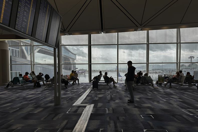 Viajeros esperando en la terminal de salidas en el aeropuerto internacional de Hong Kong, el domingo 8 de octubre de 2023. Decenas de vuelos se cancelaron el domingo conforme la tormenta tropical Koinu cerca de la ciudad sureña china, después de matar a una persona y dejar 300 heridos en Taiwán. (AP Foto/Emily Wang)