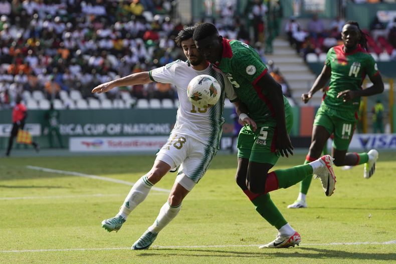 Mohamed Amoura de Argelia pelea por el balón con Nasser Djiga de Burkina Faso en el encuentro del Grupo D de la Copa Africana de Naciones en Costa de Marfil el sábado 20 de enero de 2024. (AP Foto/Themba Hadebe)