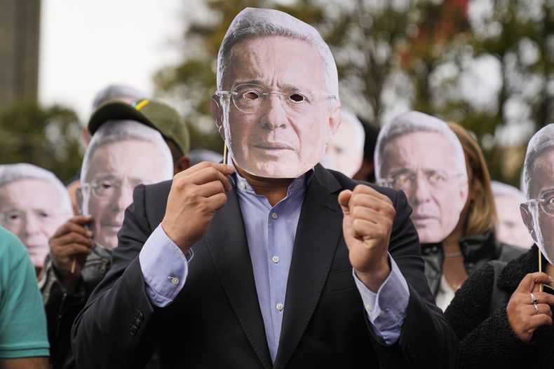 Partidarios del expresidente colombiano Álvaro Uribe sostienen recortes de su rostro afuera del tribunal donde se espera un veredicto en su juicio por manipulación de testigos en Bogotá, Colombia, el lunes 28 de julio de 2025. (AP Foto/Fernando Vergara)
