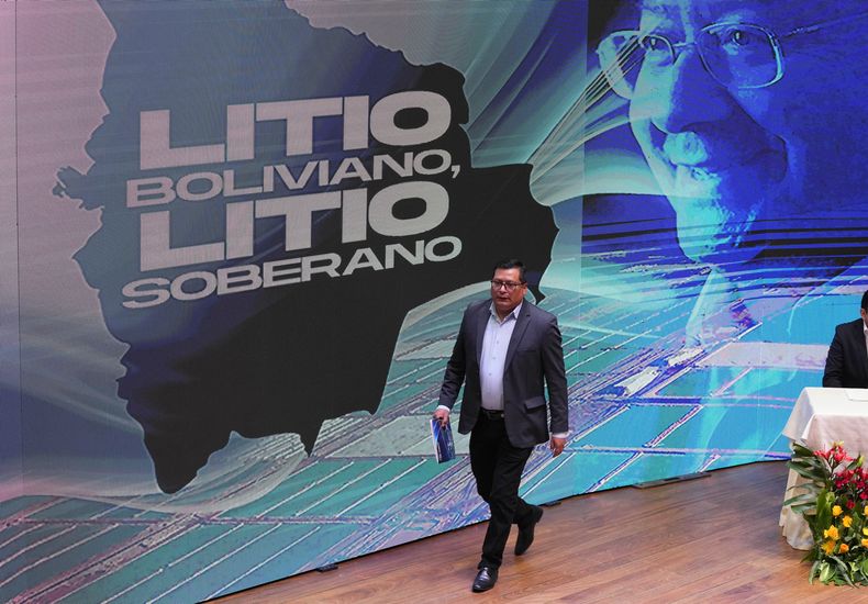 Carlos Ramos, presidente de la empresa estatal Yacimientos de Litio Bolivianos (YLB), cruza el escenario durante la ceremonia de firma de un convenio con las empresas Uranium One Group, subsidiaria de la rusa Rosatom, y la china Citic Guoan Group en el palacio de gobierno en La Paz, Bolivia, el jueves 29 de junio de 2023. (AP Foto/Juan Karita)