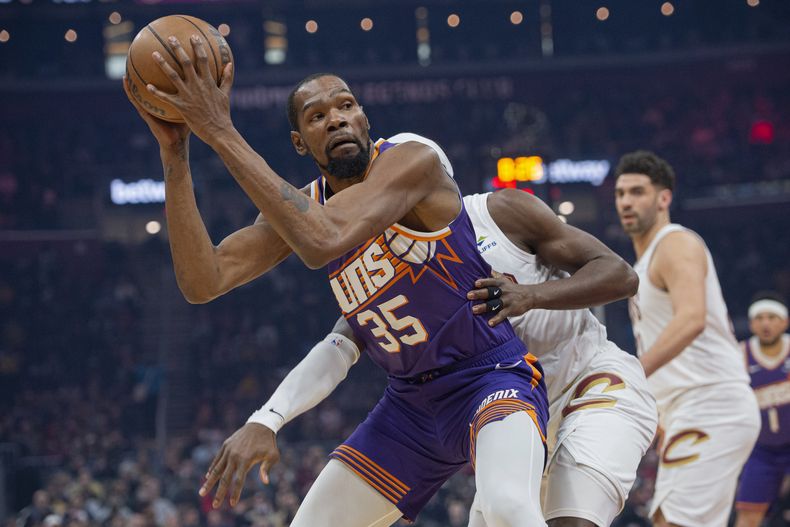 Kevin Durant (35), de los Suns de Phoenix, se alista para intentar una canasta ante la presión defensiva de Caris LeVert, de los Cavaliers de Cleveland, durante la primera mitad del juego de baloncesto de la NBA, en Cleveland, el 11 de marzo de 2024. (AP Foto/Phil Long)