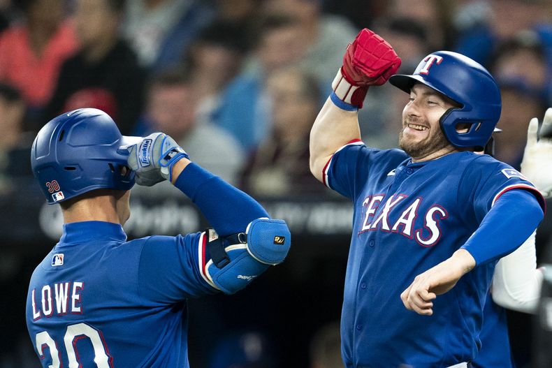 Nathaniel Lowe, de los Rangers de Texas, festeja con Robbie Grossman su jonrón de tres carreras en el juego del miércoles 13 de septiembre de 2023, ante los Azulejos de Toronto (Spencer Colby/The Canadian Press via AP)