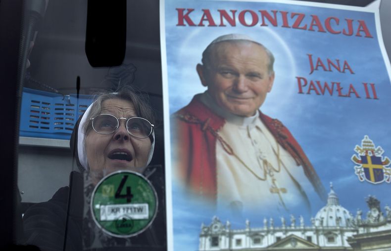 Una monja cat&oacute;lica gesticula luego de colocar un cartel del difunto papa Juan Pablo II en el parabrisas de un autob&uacute;s, en Wadowice, Polonia, el viernes 25 de abril de 2014. Dos autobuses partieron de Wadowice hacia Roma para que peregrinos p
