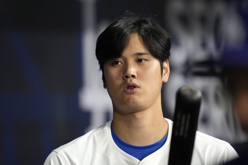 El bateador designado de los Dodgers de Los Ángeles Shohei Ohtani de pie en el banquillo durante la primera entrada del juego de béisbol ante los Padres de San Diego, en el Gocheok Sky Dome, en Seúl, Corea del Sur, el jueves 21 de marzo en Seúl, Corea del Sur. (AP Foto/Lee Jin-man)