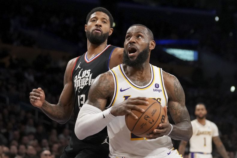 El jugador de los Lakers de Los Ángeles LeBron James, delante a la derecha, se acerca a la canasta ante el jugador de los Clippers de Los Ángeles Paul George (13) en la primera mitad de su juego de NBA en Los Ángeles, el domingo 7 de enero de 2024. (AP Foto/Eric Thayer)