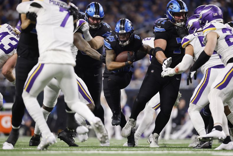 Jahmyr Gibbs (26), running back de los Lions de Detroit, corre por un hueco que le abrieron sus linieros ofensivos frente a los Vikings de Minnesota durante la segunda mitad del partido de la NFL del domingo 5 de enero de 2025, en Detroit. (AP Foto/Rey Del Rio)