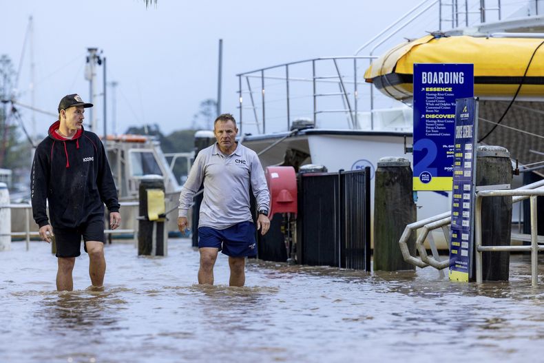 Conor Lang y Anthony Heeney caminan por zonas inundadas en Port Macquarie, al norte de Sydney, Australia, el miércoles 21 de mayo de 2025. (Lindsay Moller/AAP Image via AP)