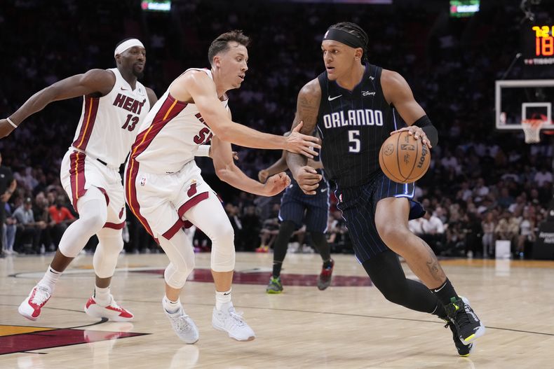 Paolo Banchero, del Magic de Orlando, conduce el balón hacia la cesta frente a Duncan Robinson y Bam Adebayo, del Heat de Miami, el miércoles 23 de octubre de 2024 (AP Foto/Wilfredo Lee)